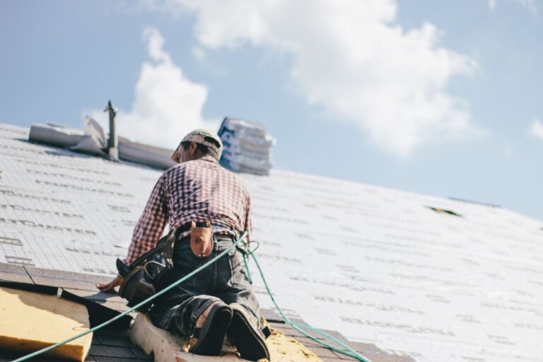 En byggarbetare lägger isolering innan nytt tak är på plats