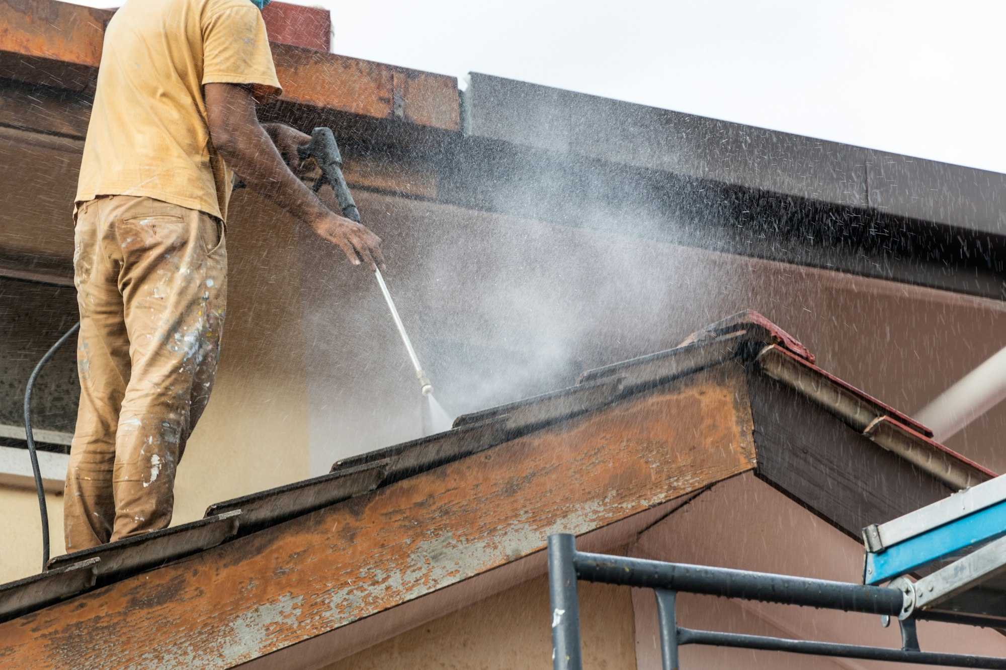 Arbetare som använder högtrycksvattensprutpistol för att tvätta och rengöra smuts från takpannor